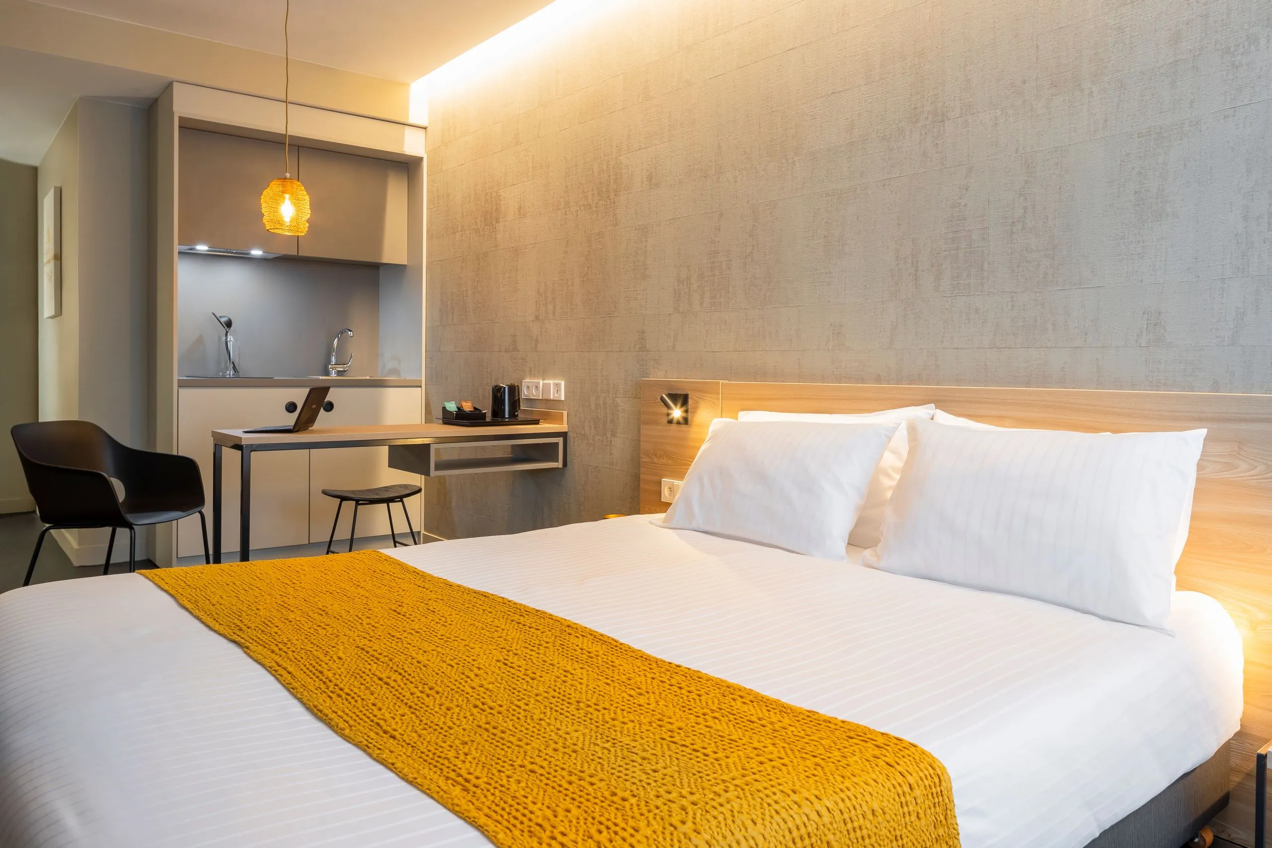 Chambre d'hôtel moderne avec lit et coin cuisine 